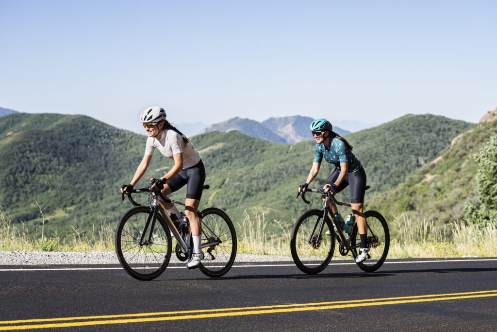 Duas ciclistas na estrada entre montanhas